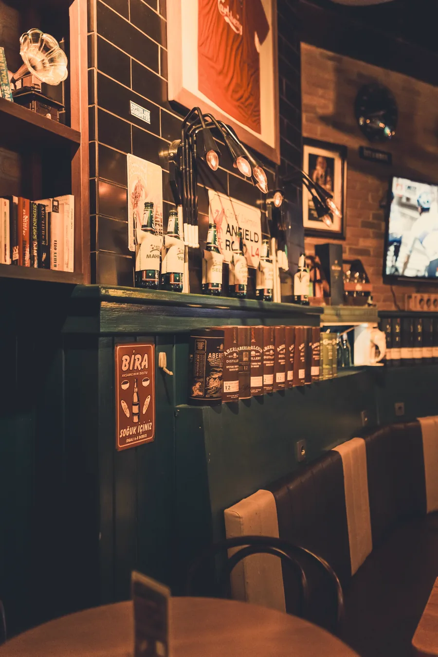 A warm-lit bar with a stocked back shelf and green tiles